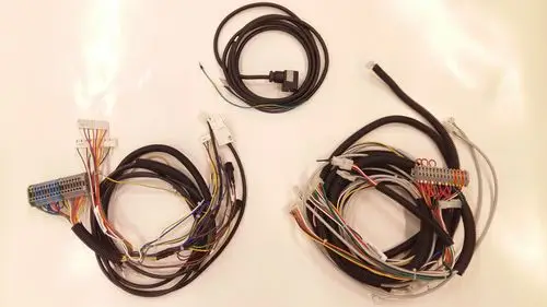Drei Kabelbündel mit verschiedenen Steckverbindern und Drähten, die zu einem Remeha Produkt gehören. Kabel sind übersichtlich angeordnet und teilweise mit Schrumpfschlauch versehen.
